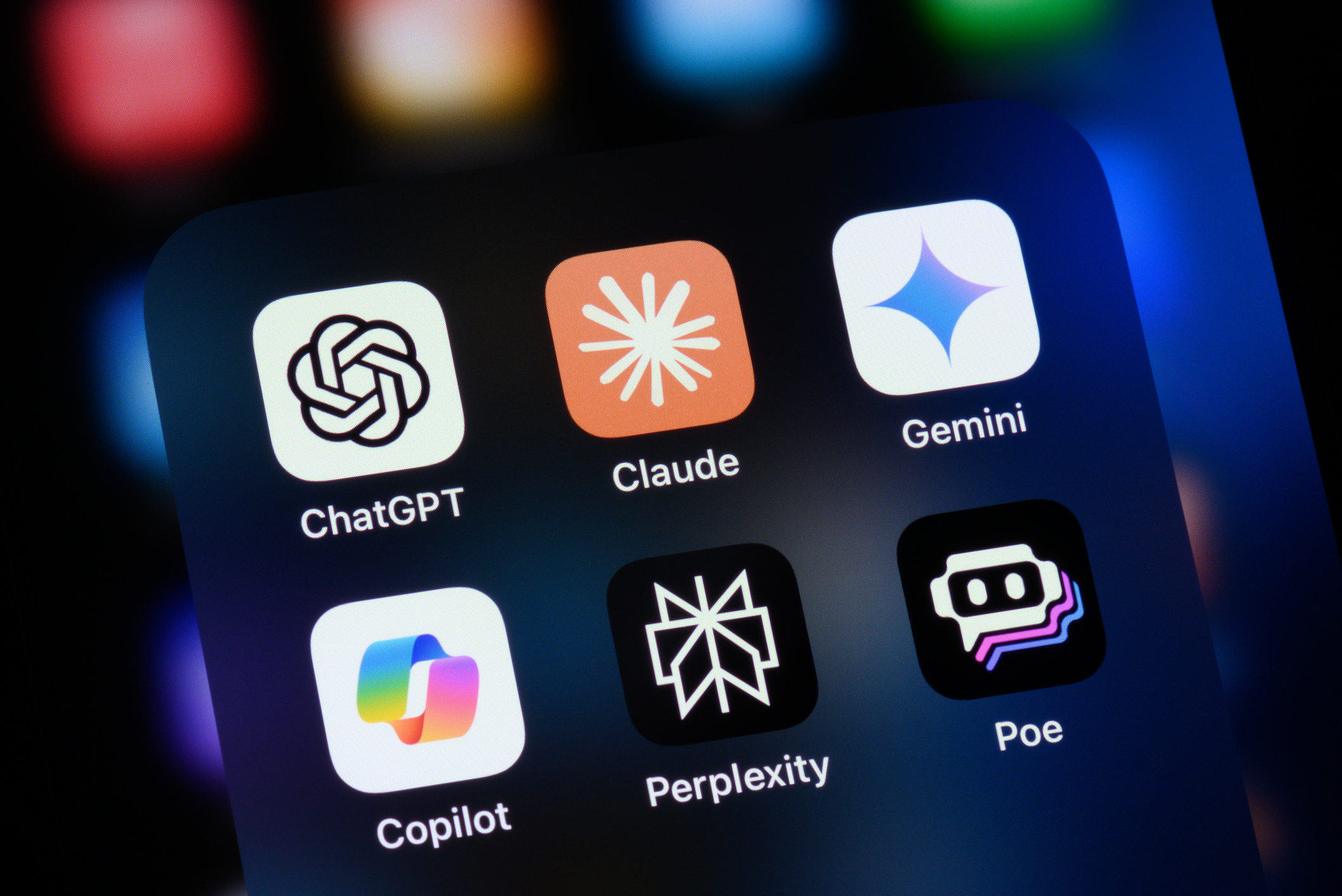 Close-up of a smartphone screen displaying six popular AI chatbot app icons: ChatGPT, Claude, Gemini, Copilot, Perplexity, and Poe.
