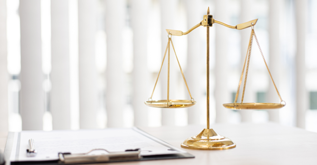 A gold balance scale representing law and justice, positioned on a desk beside legal documents.