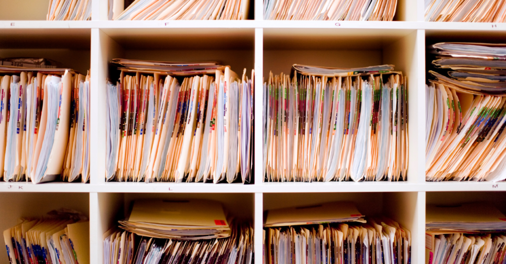 Shelves filled with organized paper files and folders in an office filing system.