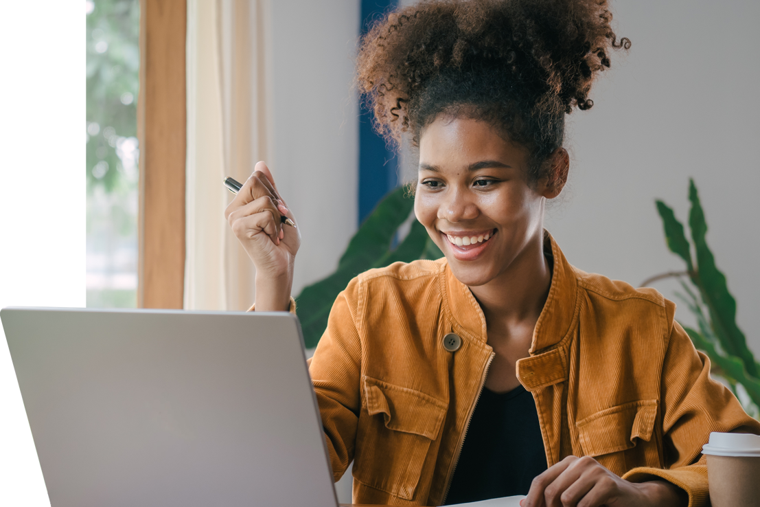 Smiling young woman learning online, sitting at a laptop. She's representing FreeCampus’s free, accessible online courses.